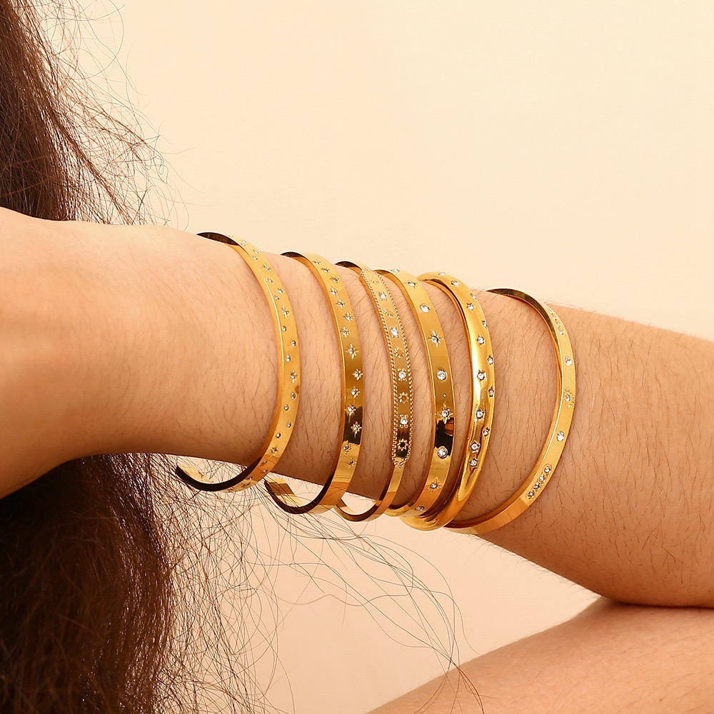 Celeste™ 18K gold plated stainless steel slim bangle featuring sparkling crystal star detailing and a polished hinged design.