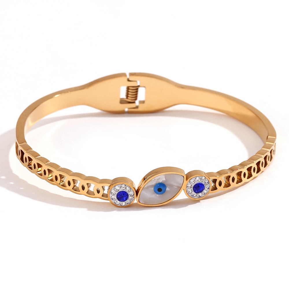 Nazaré 18K gold plated stainless steel evil eye crystal bangle featuring a mother-of-pearl style centrepiece, blue crystal accents and a secure hinged clasp.